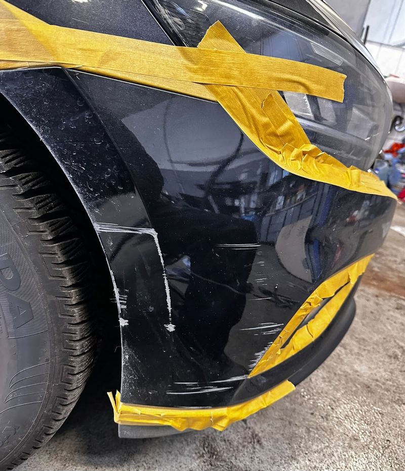 VW Passat mit Kratzern am vorderen Stoßfänger, für die Reparatur abgeklebt